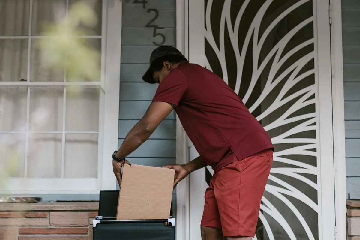 Entregador deixando uma caixa na porta de uma casa
